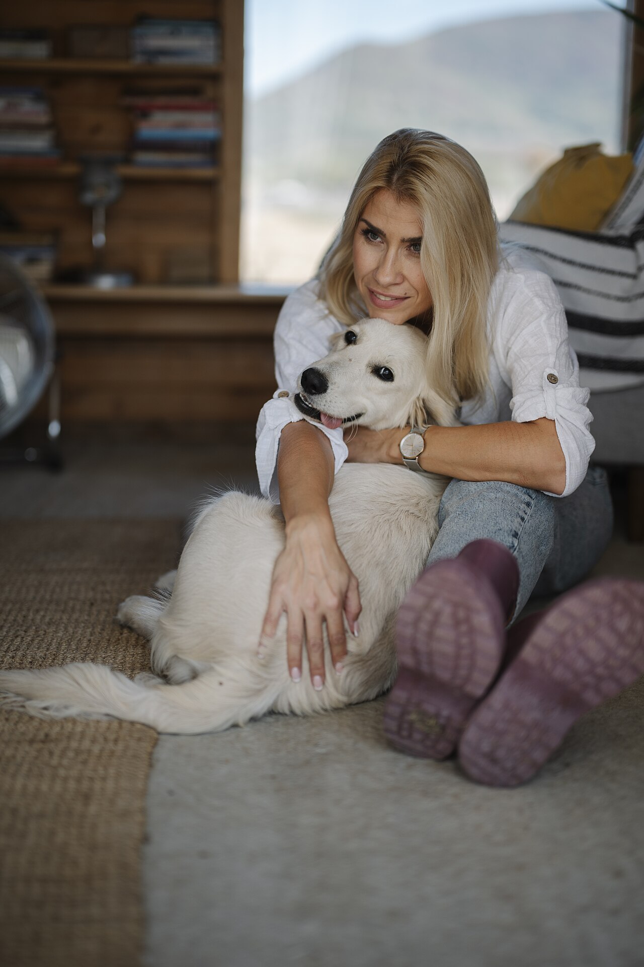 Woman cuddling her happy dog on the floor at home